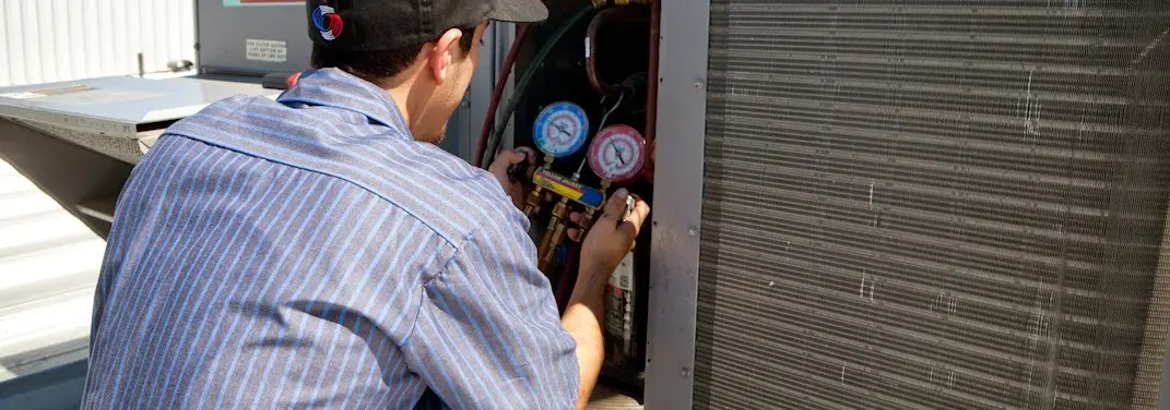 HVAC technician servicing a condenser unit in Montevallo